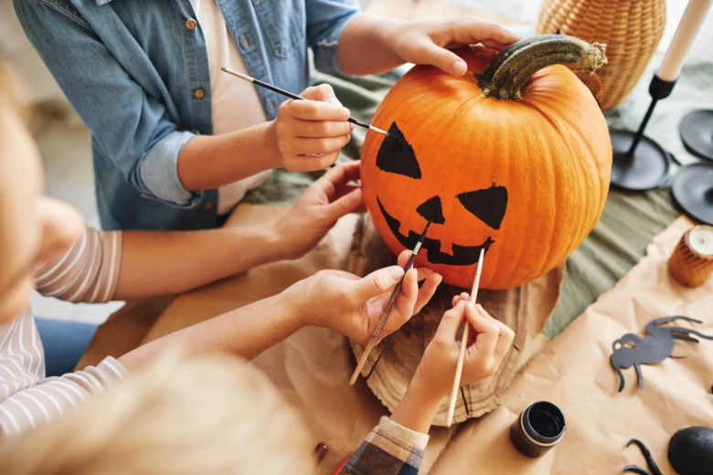 Malování na dýni: děti malují tvář halloweenskou pumpičky.
