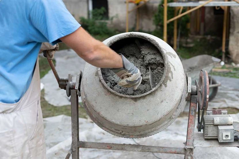Ruční míchání betonu v bubnovém smíchávači na staveništi.