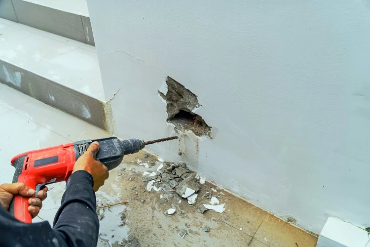 Osoba vrtá do zdi pomocí vrtáku