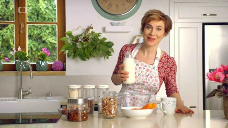 Žena s mlékem v kuchyni připravuje zdravé koláčové suroviny.