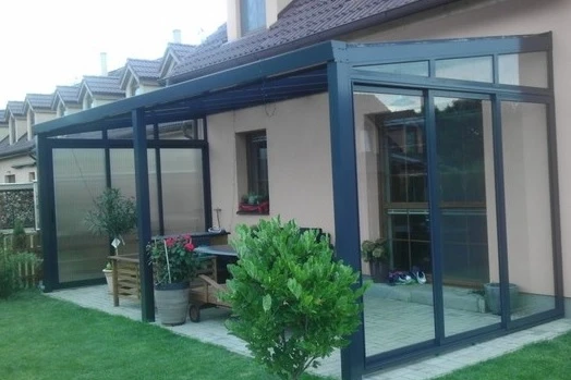 Moderní zimní zahrada přistavěná k domu s skleněnými stěnami.