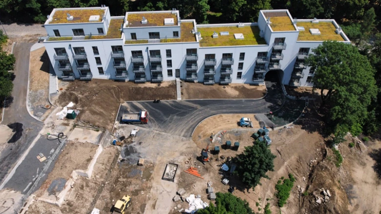 Nová budova s dokončenými fasádami na staveništi v plné výstavbě.