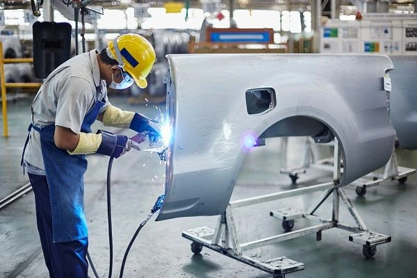 Welder working on car part