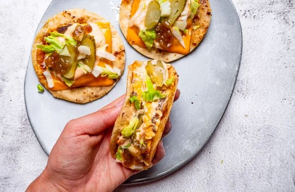 Mexické taco s syrem, okurkou a zeleninou na talíři.