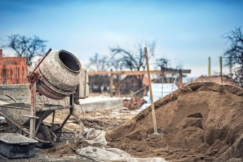 Staveniště s betonovou směšovačkou a pískem pro výrobu lehčeného betonu.