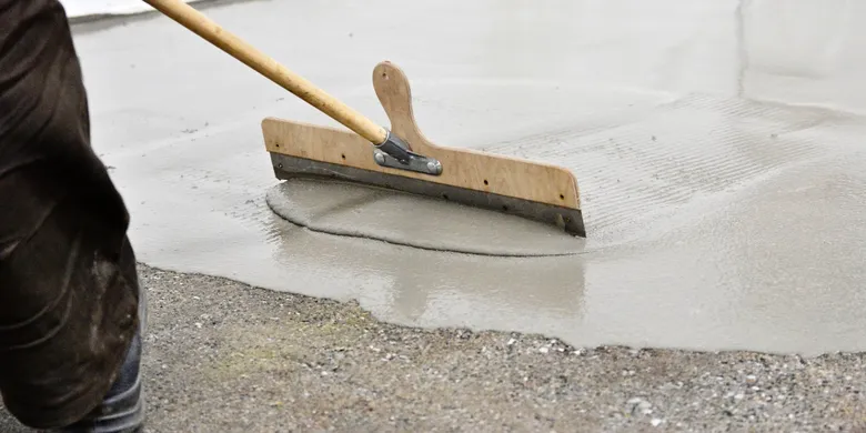 Pracovník hladí betonovou podlahu v garáži