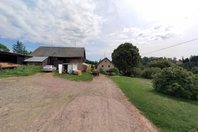 Venkovská farma s stodolami, seny a auty na zemi.
