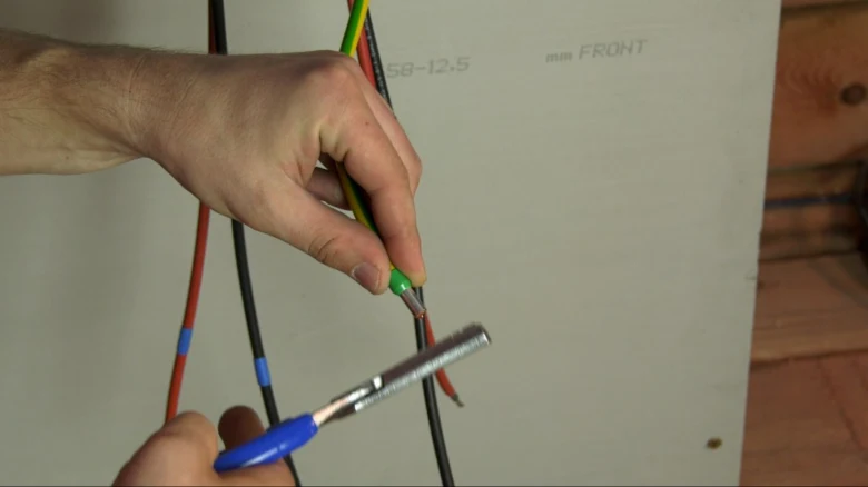 Ruční odstraňování izolace z elektrického kabelu.