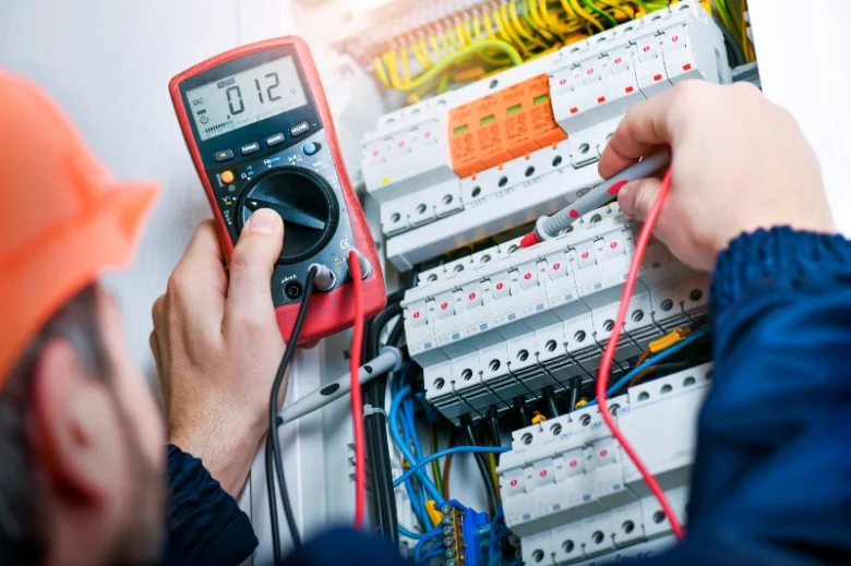 Elektrikář měří napětí v rozvaděči multimetrem při opravách.