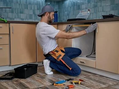 Renovace kuchyně: instalace skříní s náradím na podlaze.