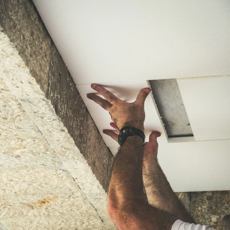 Ruční instalace izolačního materiálu do stropního prostoru.
