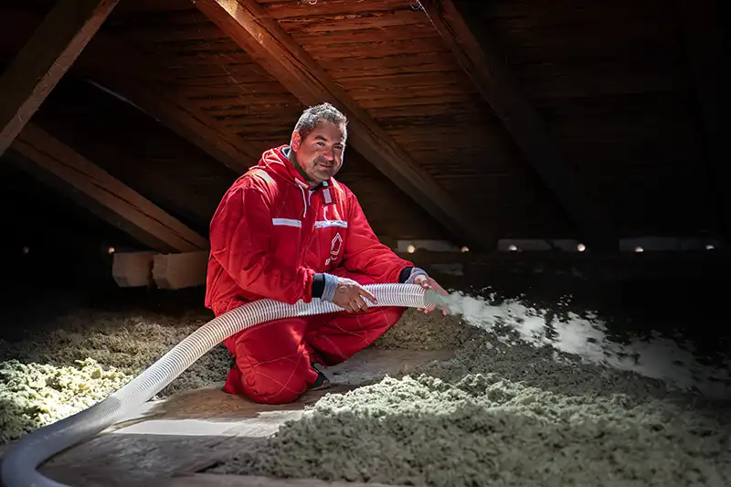 Pracovník izoluje strop pod střechou bez parozábrany.