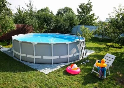 Hotový nadzemní bazén v zahradě s lehátky a hračkami