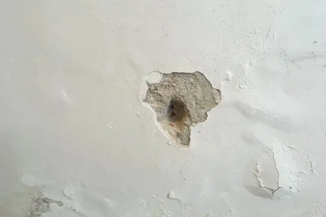 Poškozená omítka na zdi před opravou