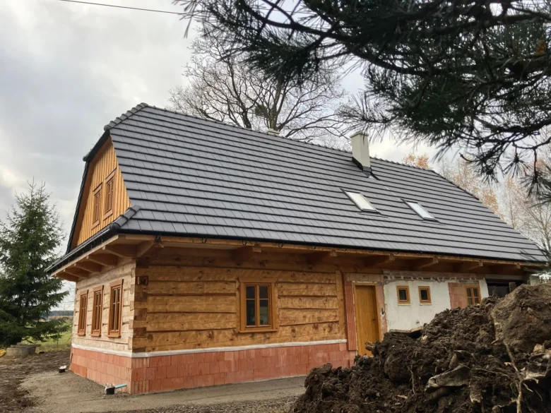Tradiční roubenka v procesu renovace s novou střechou a dřevěnými okny.