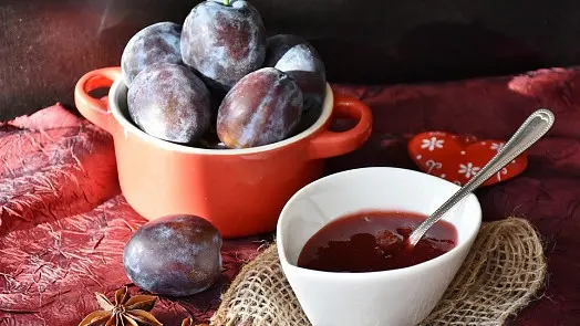 Čerstvé švestky v misce s domácí marmeládou.