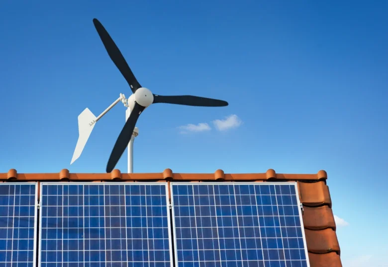 Malá větrná turbína na střechě s fotovoltaickými panely.