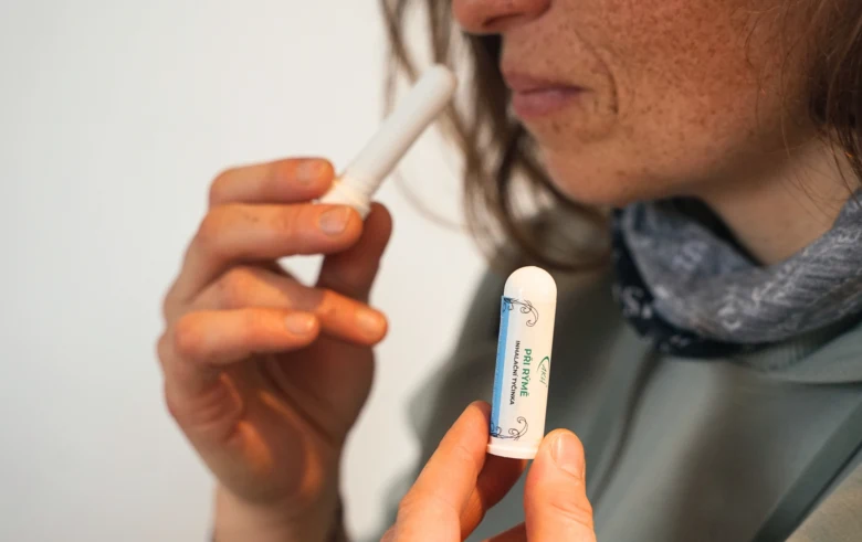 Osoba drží hůlku proti komárům u nosu pro ochranu před klíštěm.