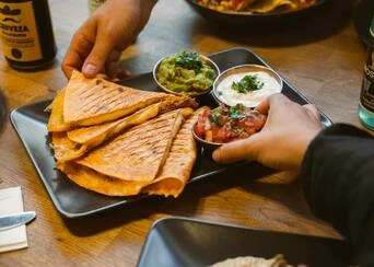 Tradiční mexické quesadily s dipem na talíři.