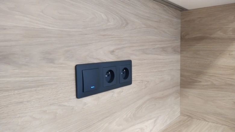 Modern elektrická zásuvka na dřevěné stěně v interiéru.