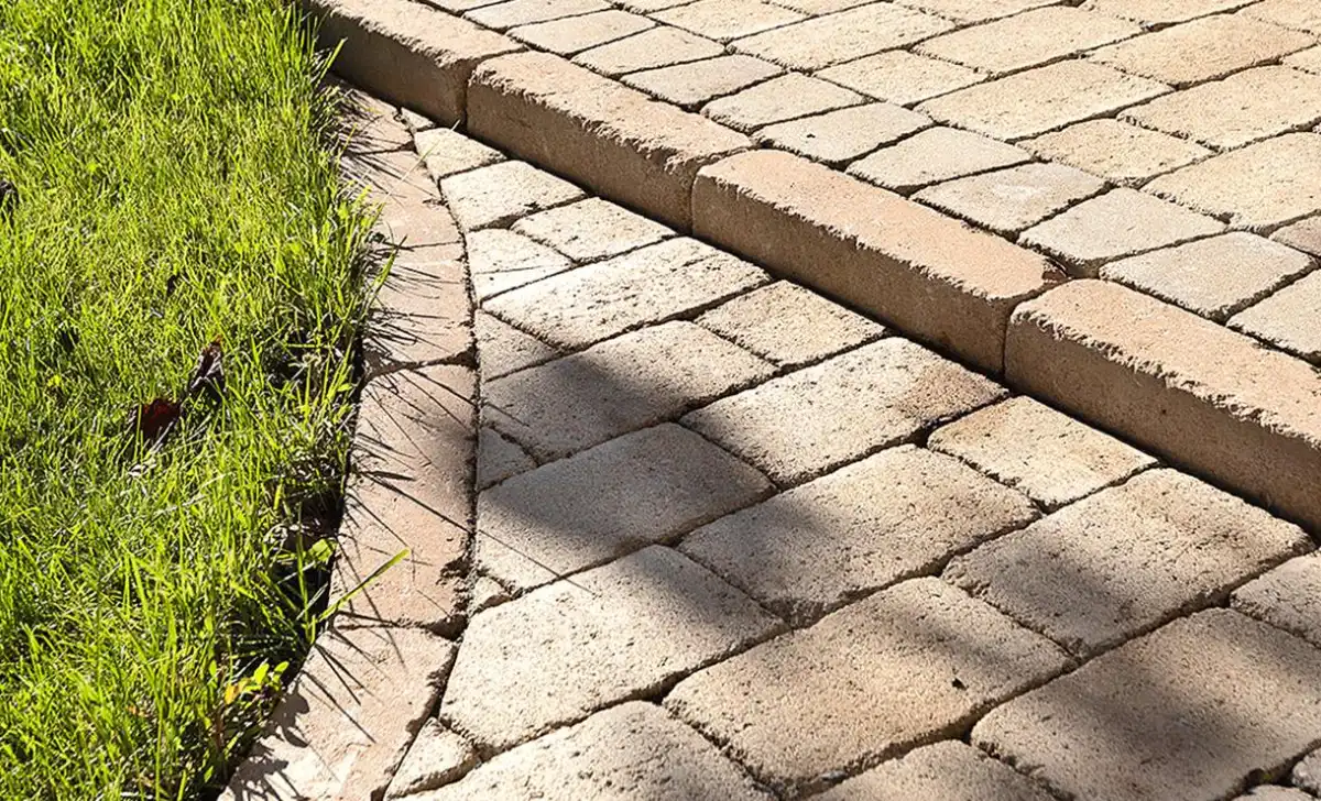 Betonový obrubník vedle trávníku a dlažby.
