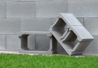 Sedmičkové betonové bloky na trávníku před zdí.