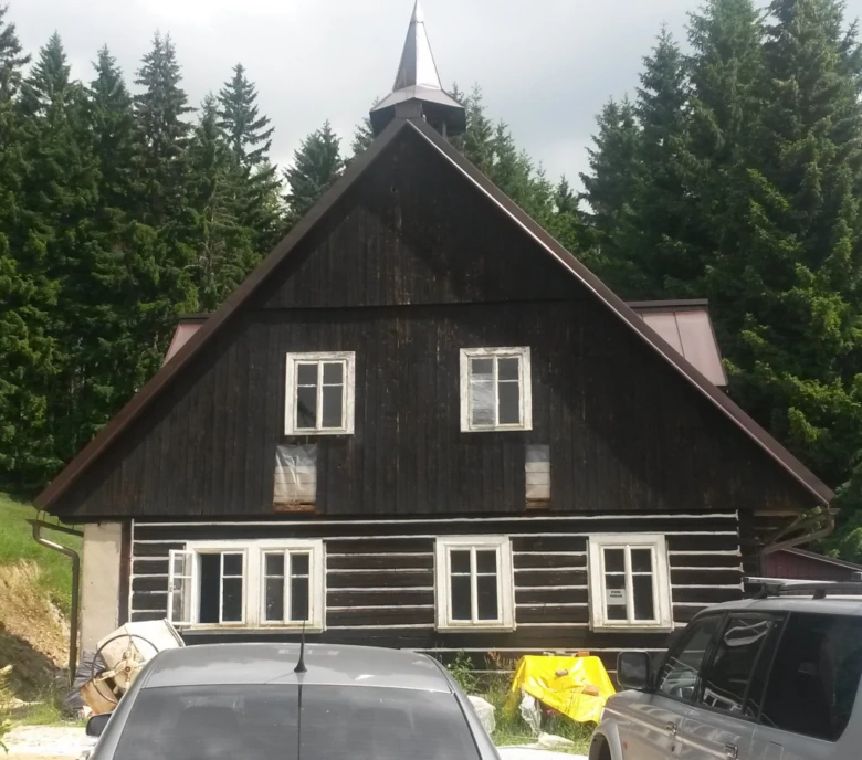 Stará roubenka před renovací s viditelným opotřebením dřeva.