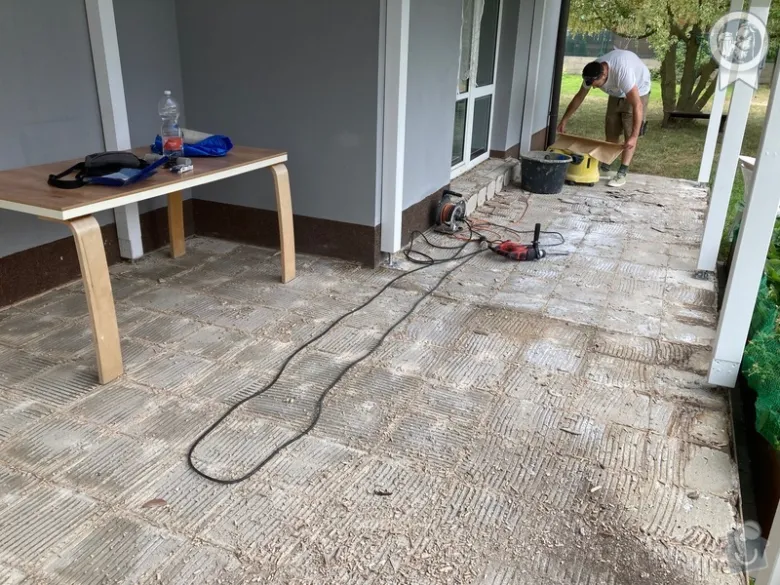 Muž montuje betonovou dlažbu na terase s nástroji.