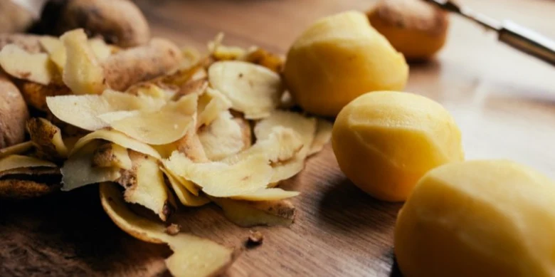 Čerstvé brambory s kůrkami na dřevěném prknu