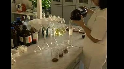 Žena v laboratoři nalévá chemikálii do zkumavek.