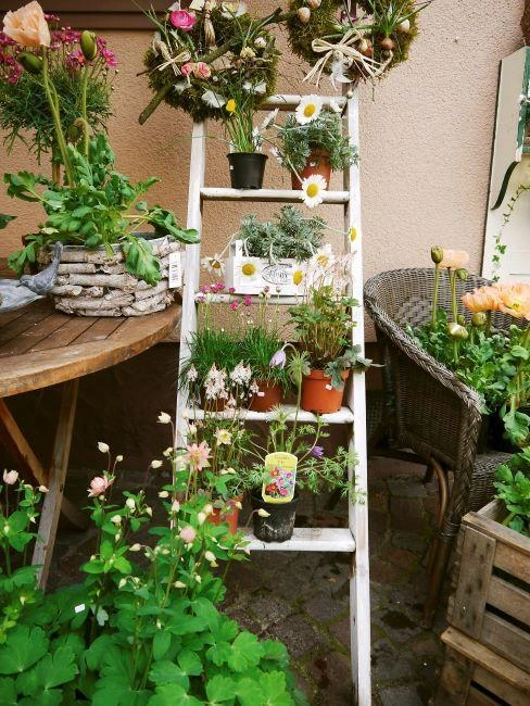 Bílá schodiště s květinami v hrncích na balkóně.