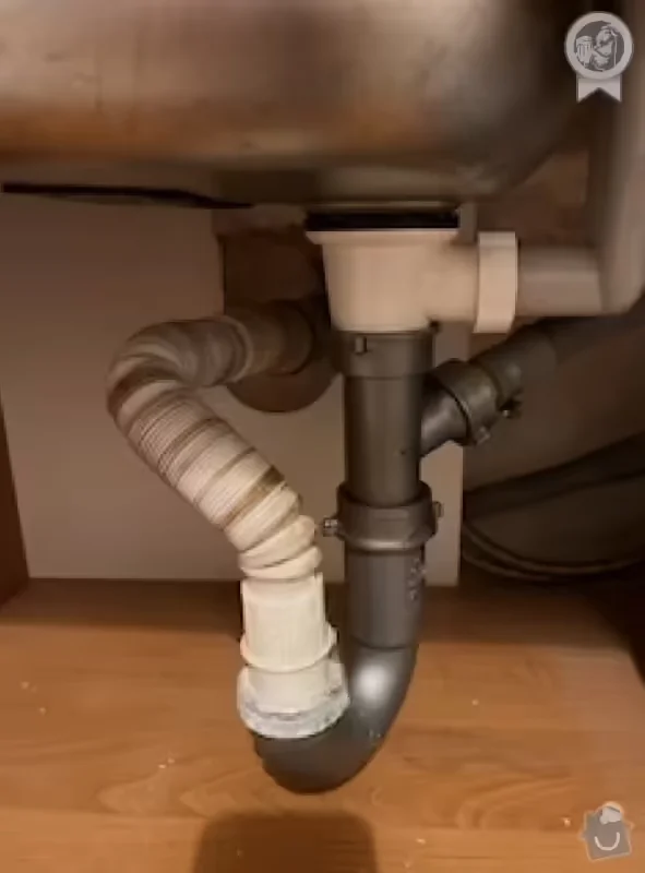 Pod umyvadlem vidíme hadici a potrubí pro odvod vody.