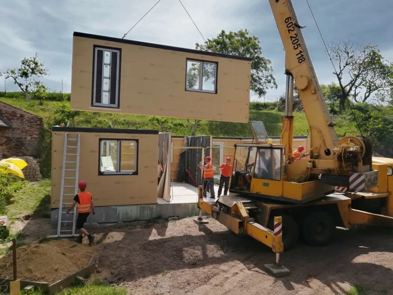 Montáž modulového domu pomocí žeriava na staveništi.