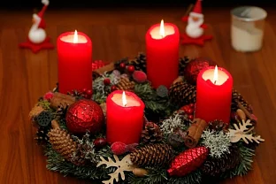 Adventní věnec s červenými svíčkami na stolu.