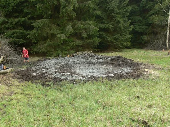 Výkop pro mokřad v zahradě s kamenitou okrajovou zónou.