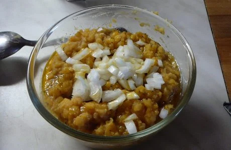 Skleněná miska s veganskou pomazánkou posypaná nakrájenou cibulí.